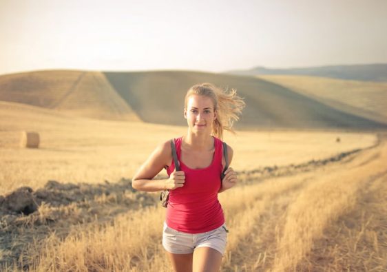 A woman jogging through vast, golden wheat fields under the summer sun, symbolizing freedom and adventure.