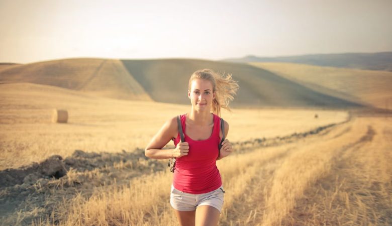 A woman jogging through vast, golden wheat fields under the summer sun, symbolizing freedom and adventure.