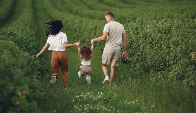 A joyful family strolls through a lush green field, enjoying quality time together.